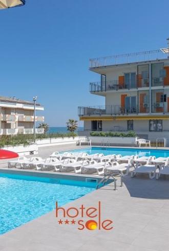 Piscina all'aperto con lettini in un hotel moderno vicino al mare.